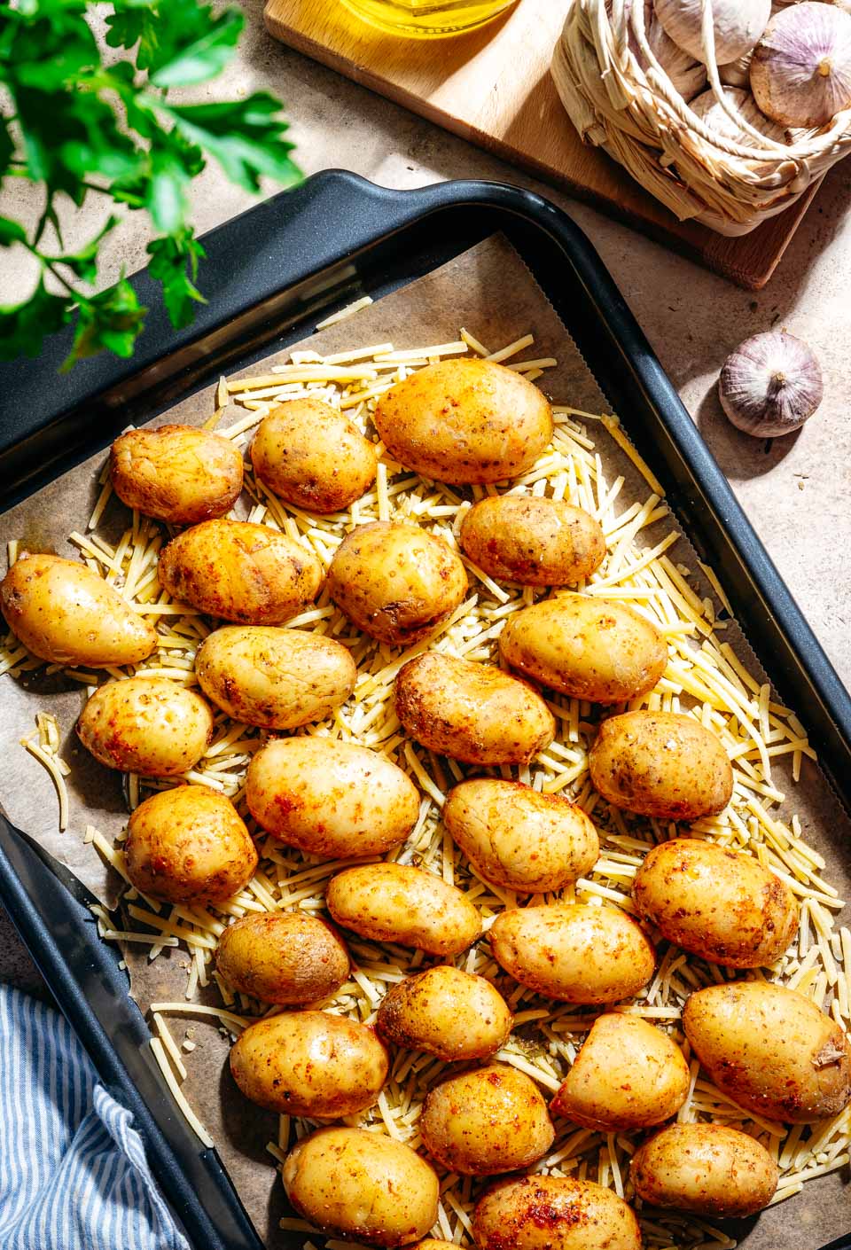 Rauwe aardappels op een bakplaat met geraspte kaas
